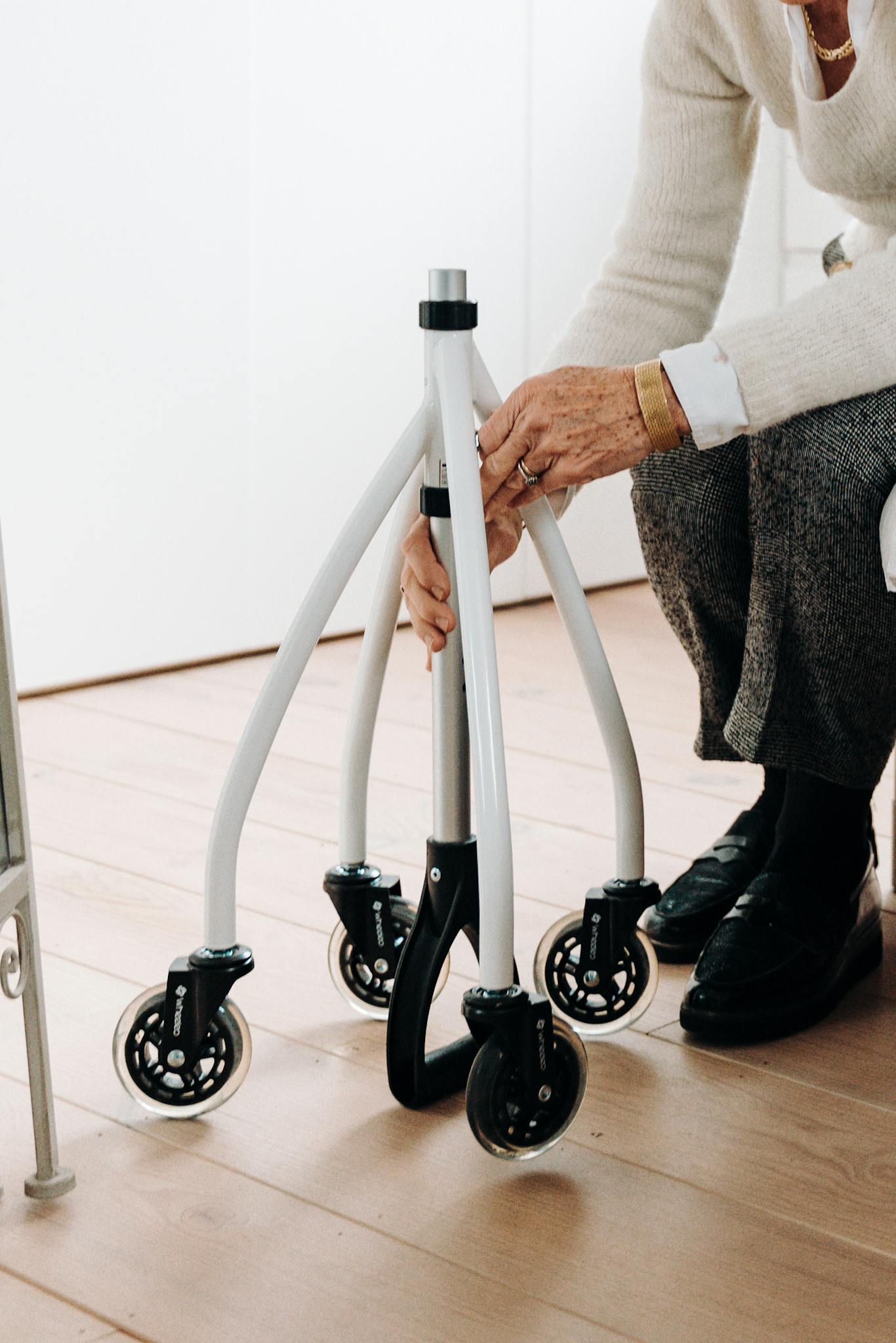 Elderly person adjusting a rollator for mobility support indoors.